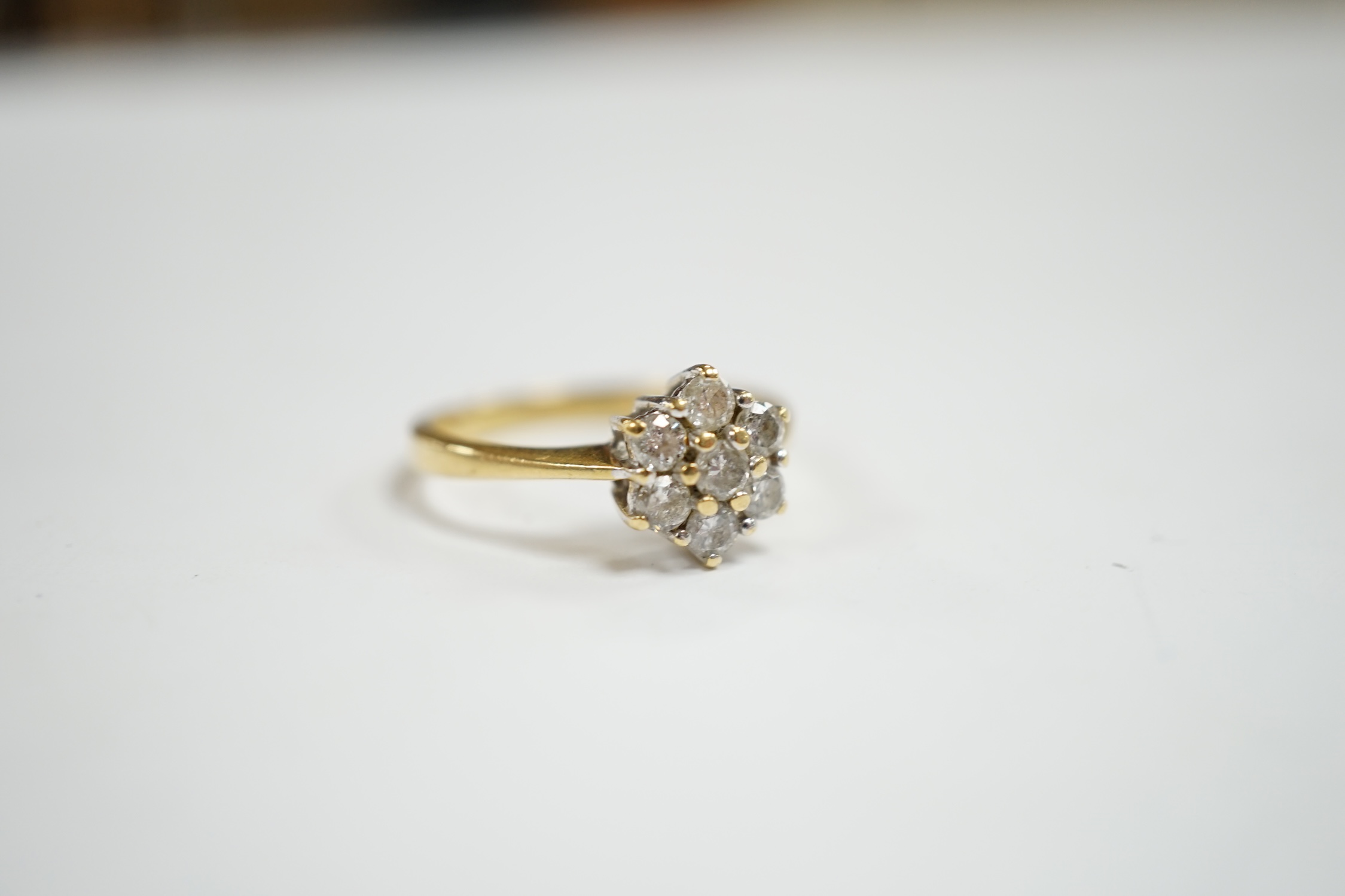 A modern 18ct gold and seven stone diamond cluster set flower head ring, size N, gross weight 3.6 grams.